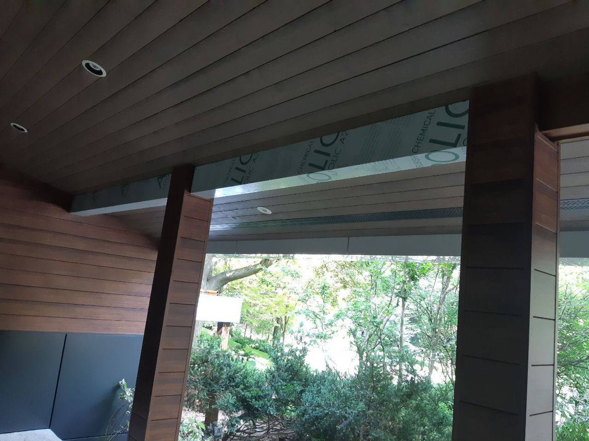 Modern wood and WPC eco-friendly exterior cladding Canada installation with lush trees.