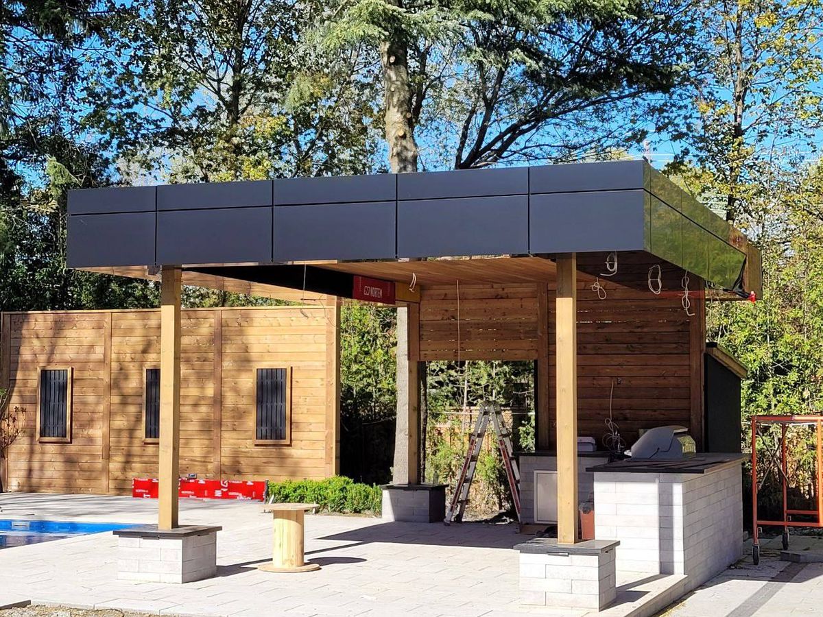 Close-up of exterior wood cladding installation with green trees in background.
