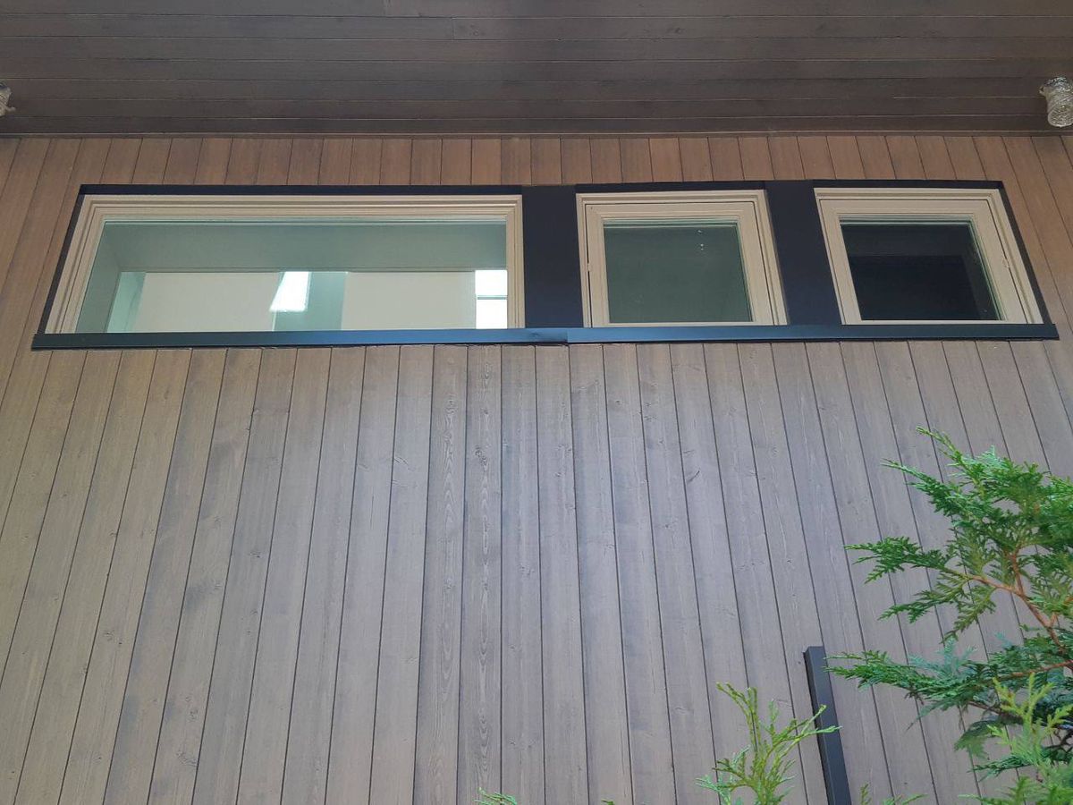 View from under a modern overhang with wood ceiling and wall cladding, overlooking trees