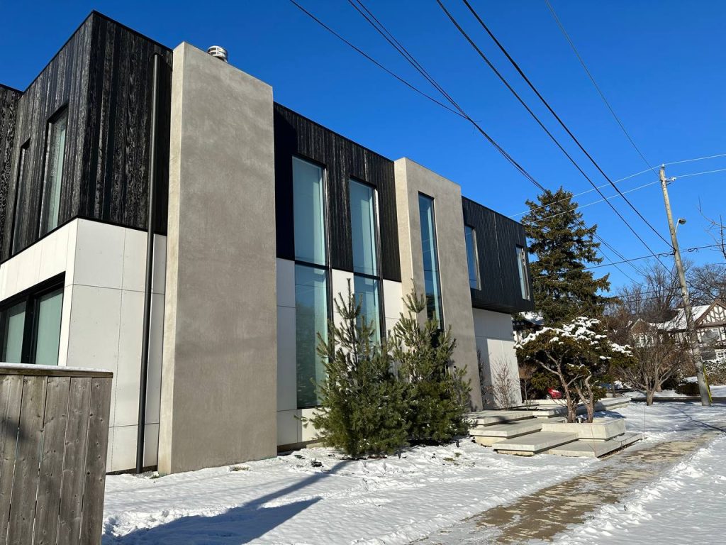 Modern house in Canadian winter with black wood and grey fiber cement vs metal cladding.